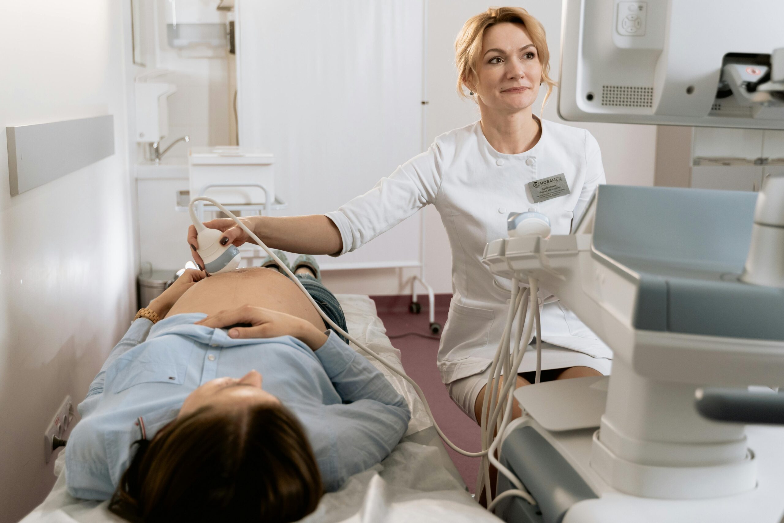 A pregnant woman receiving an ultrasound exam conducted by a healthcare professional in a medical clinic.