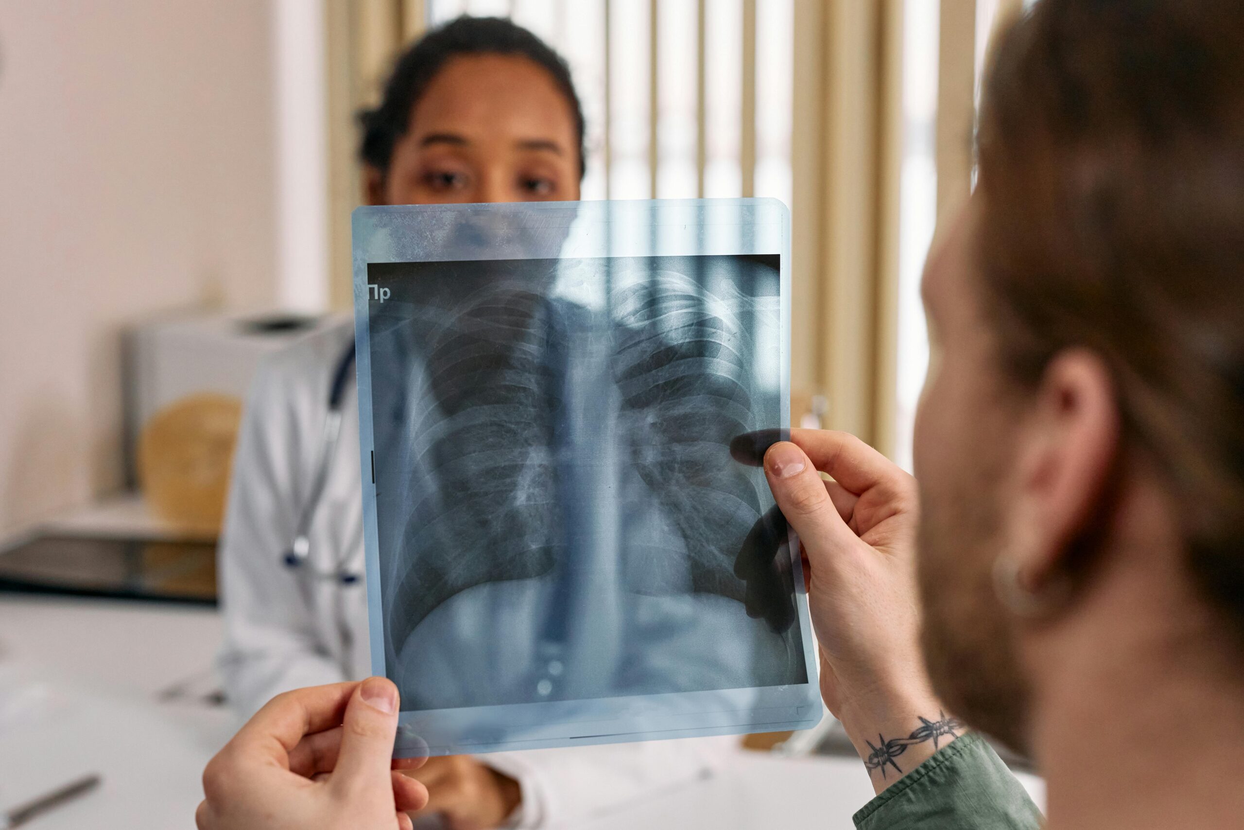 Doctor reviews chest x-ray results with patient in a medical office.